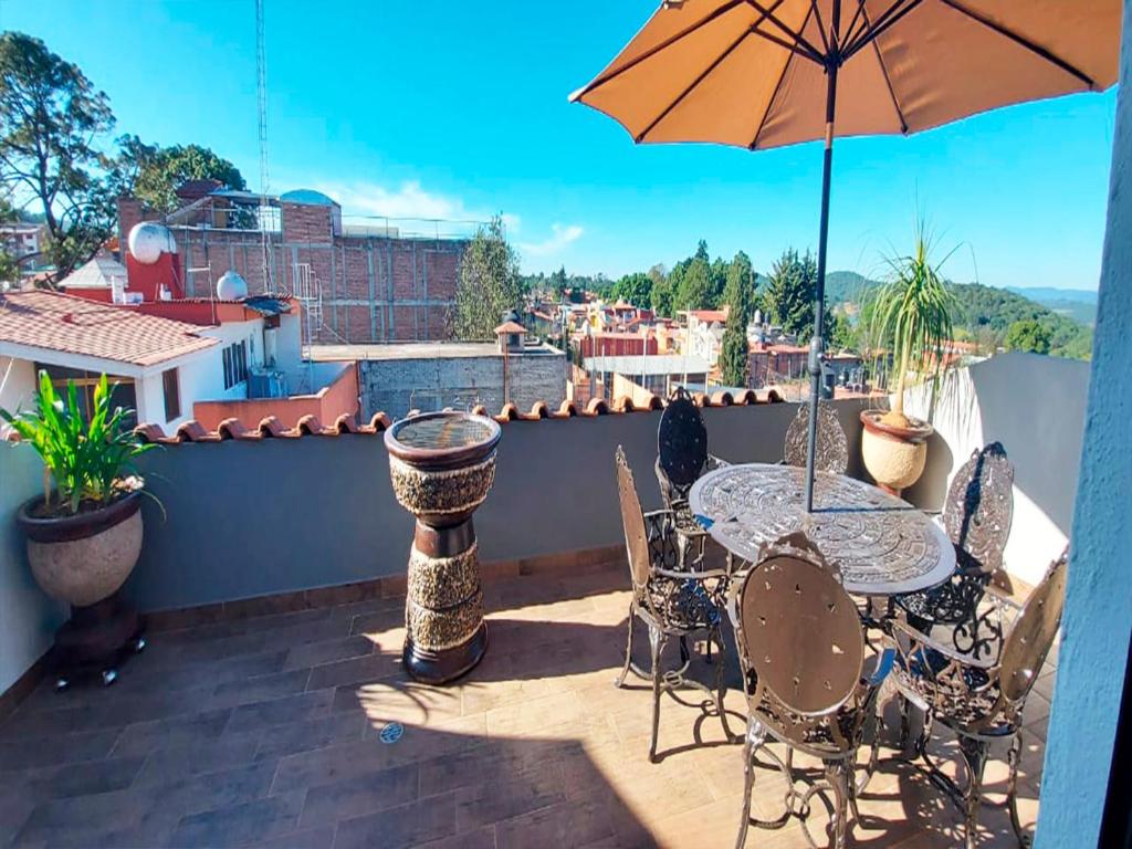 een patio met een tafel en stoelen en een parasol bij Hotel Suites La Fortuna in Mazamitla