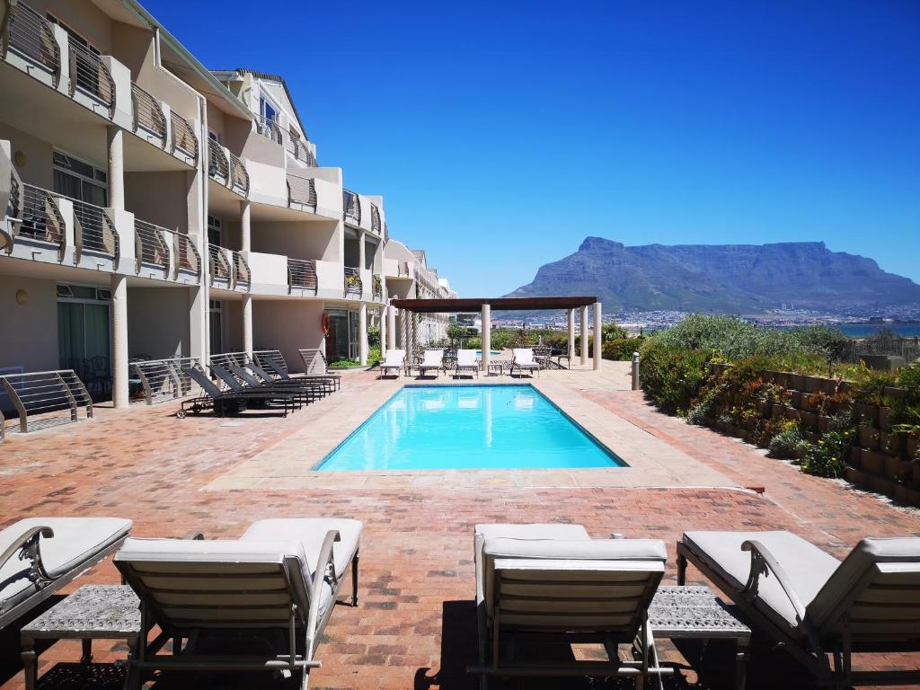 una piscina en el patio de un hotel con sillas en Cape Town Family Beachfront Apartment Leisure Bay en Ciudad del Cabo