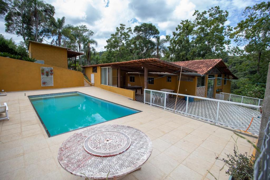 una casa con piscina y una mesa en el patio en Chácara c piscina churrasqueira e Wi-Fi em Ibiúna, en Ibiúna