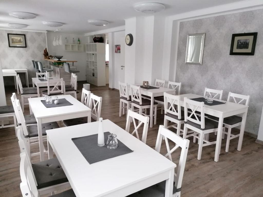 a dining room with white tables and white chairs at Pension Unikum Waldheim in Waldheim