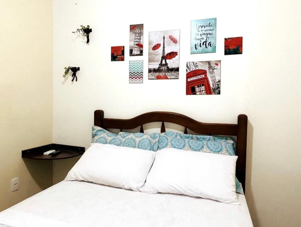 1 dormitorio con 1 cama y algunas fotos en la pared en Suíte 05 Apês do Peró - Até 3 pessoas - Centro, en Cabo Frío