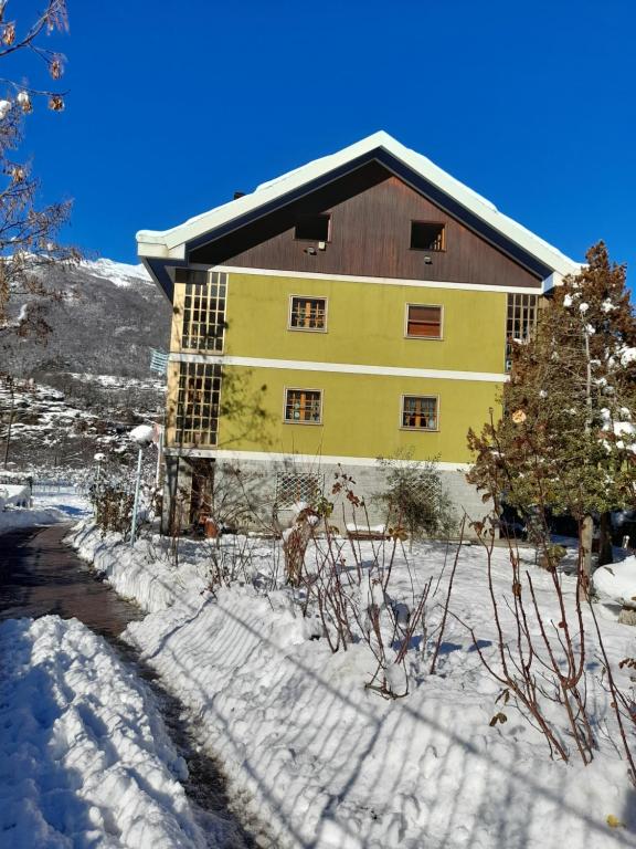 Gravere的住宿－Casa Gravere bis，一座大黄色的建筑,地面上积雪