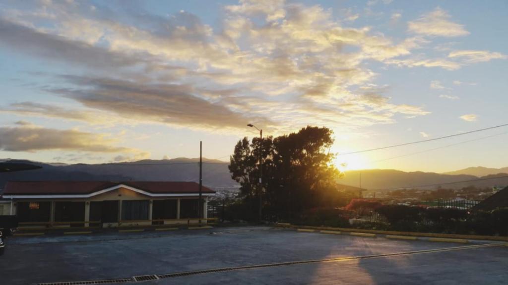 un tramonto su un parcheggio con un edificio di Hotel Las Brumas a Cartago