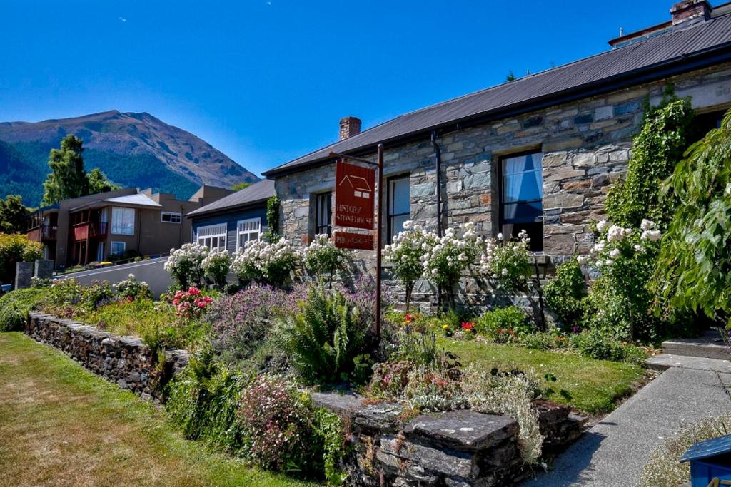 a stone house with a garden in front of it at Historic Stonehouse & Alley Cottage - Sleeps 14 with spa pool in Queenstown