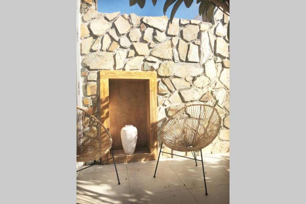 dos sillas sentadas frente a una pared de piedra en Casita blanca cerca de Timanfaya, en Tinguatón