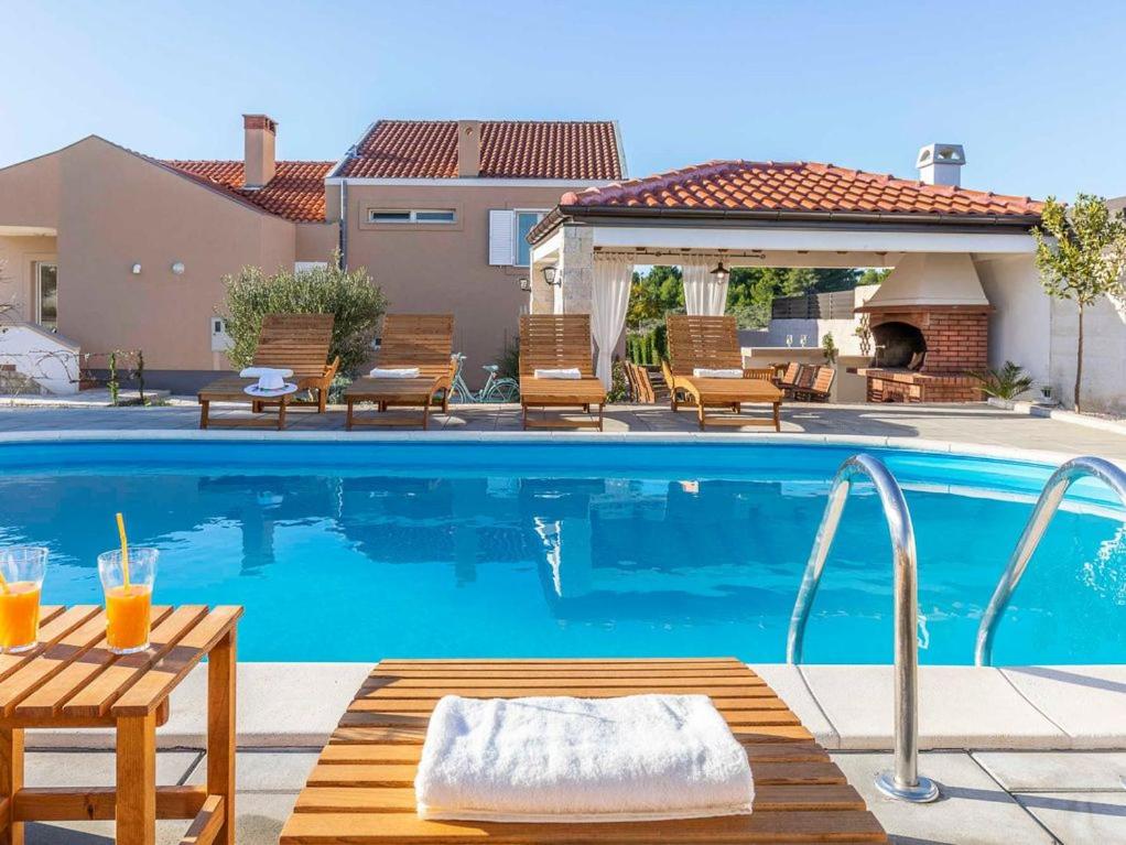 a pool with chairs and a table next to a house at Maslina in Vrsi