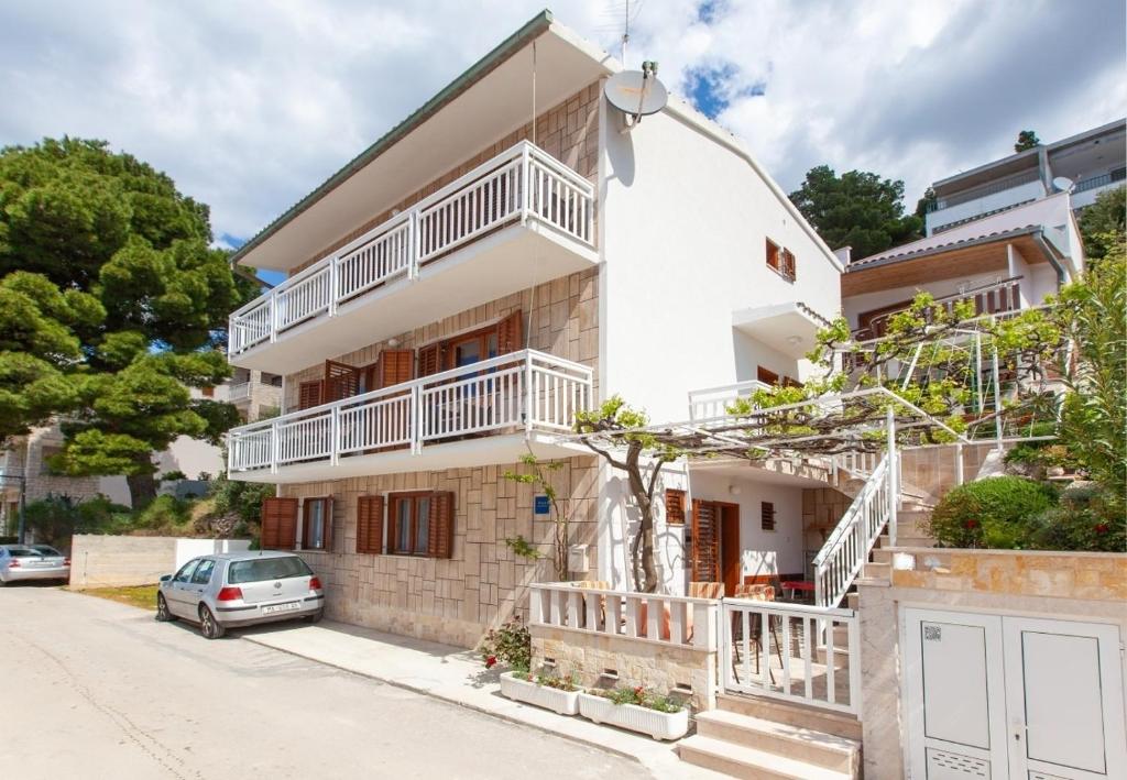 a white house with white balconies on a street at Apartments Ante-100m from beach in Brela