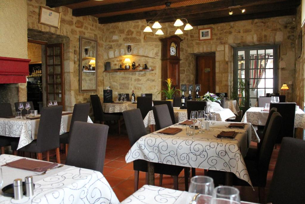 un ristorante con tavoli, sedie e orologio di Logis Hotels- Auberge de la Tour - Hôtel et restaurant a Sauzet