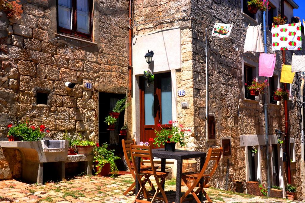 a table and chairs in front of a stone building at Cas'Antica Soprana in Petralia Soprana
