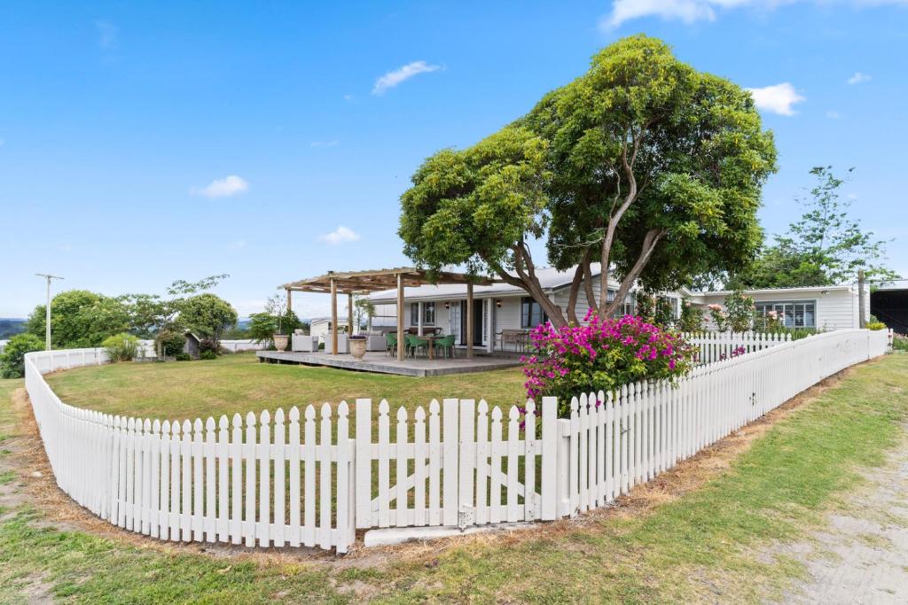 a white picket fence in front of a house at The Cottage - Te Puke Holiday Home in Te Puke