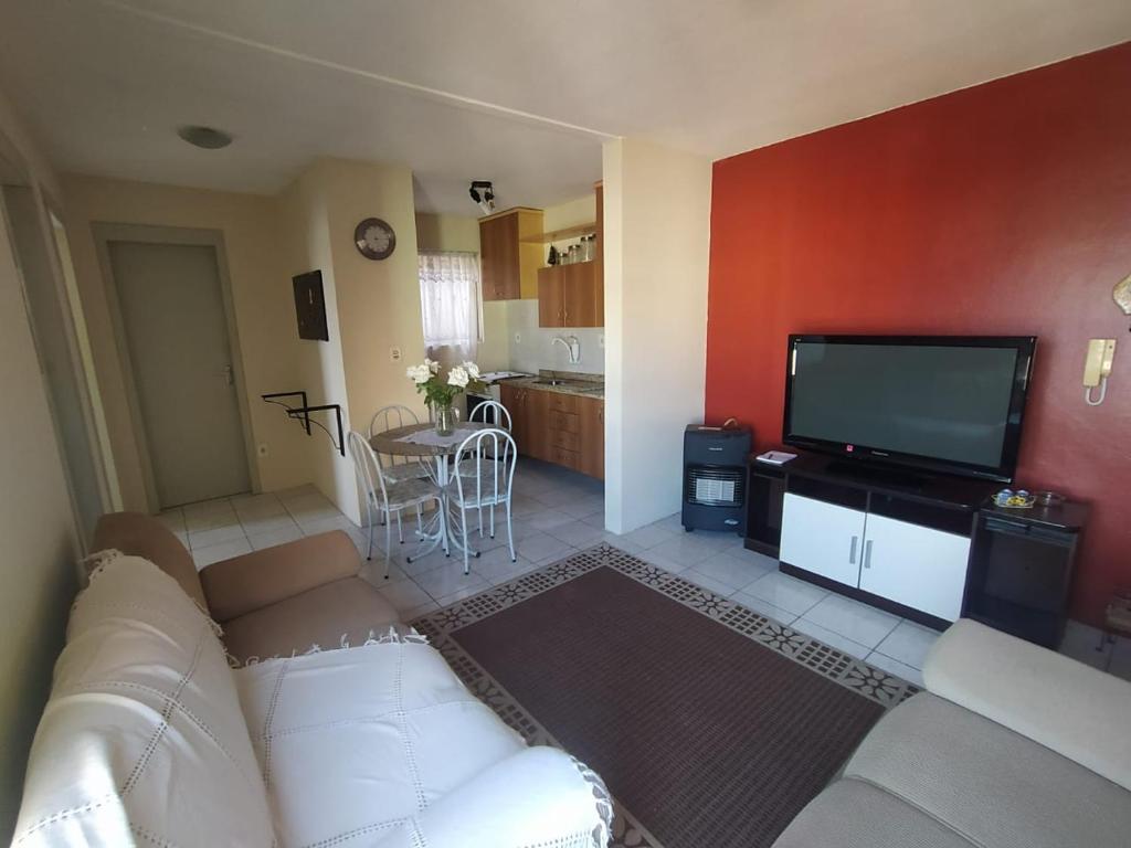 uma sala de estar com um sofá branco e uma televisão de ecrã plano em Apto 2 quartos, cond fechado, com vaga, quarto andar em Pelotas