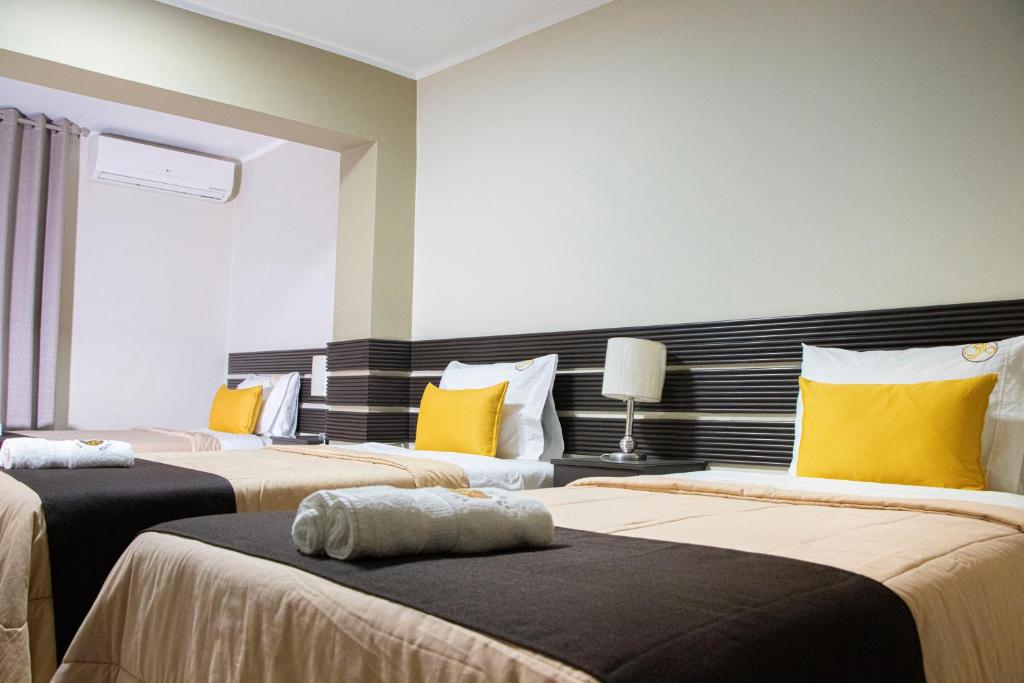 a bedroom with two beds with yellow pillows at Hotel San Martin in Tarapoto