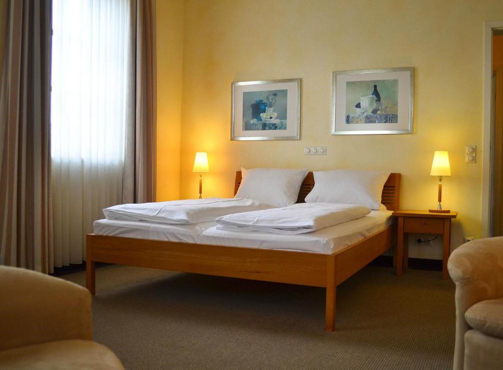 ein Schlafzimmer mit einem Bett mit zwei Lampen und zwei Stühlen in der Unterkunft Staffelsteiner Hof in Bad Staffelstein