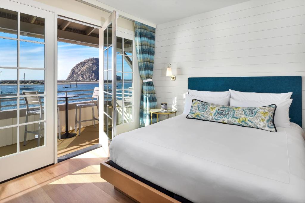 a bedroom with a bed and a balcony at Inn At Rose's Landing in Morro Bay