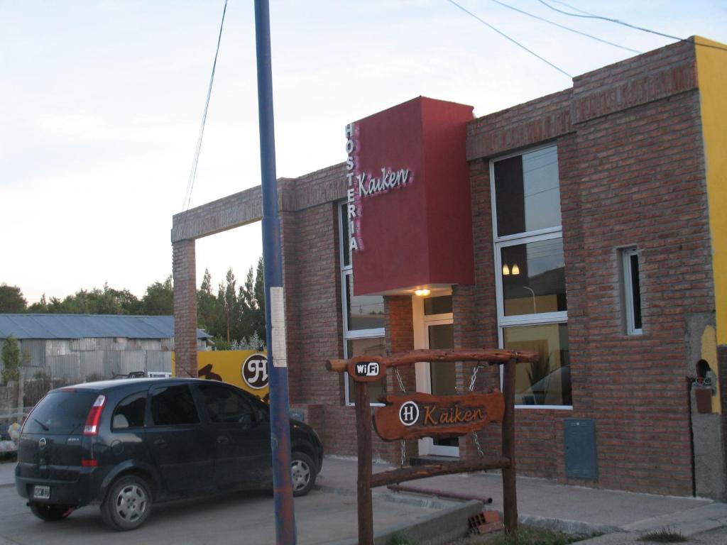 un coche aparcado frente a un edificio con una señal en Hosteria Kaiken Gregores en Gobernador Gregores