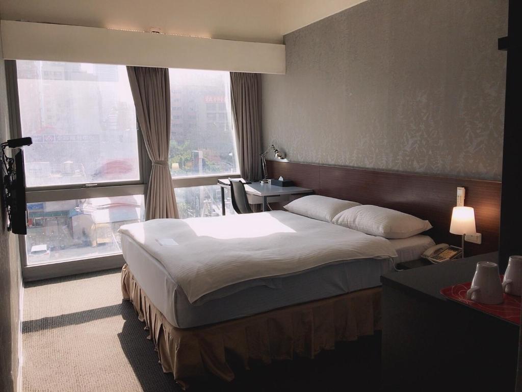 a hotel room with a bed and a large window at The Galerie Hotel in Taichung