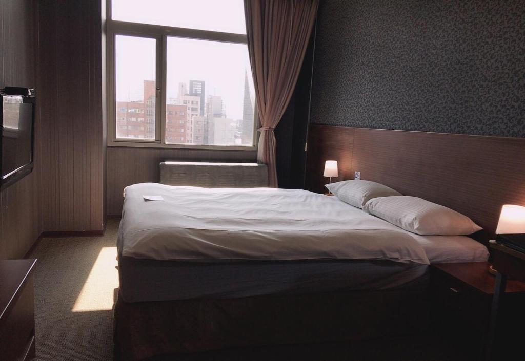 a bedroom with a large bed with a window at The Galerie Hotel in Taichung