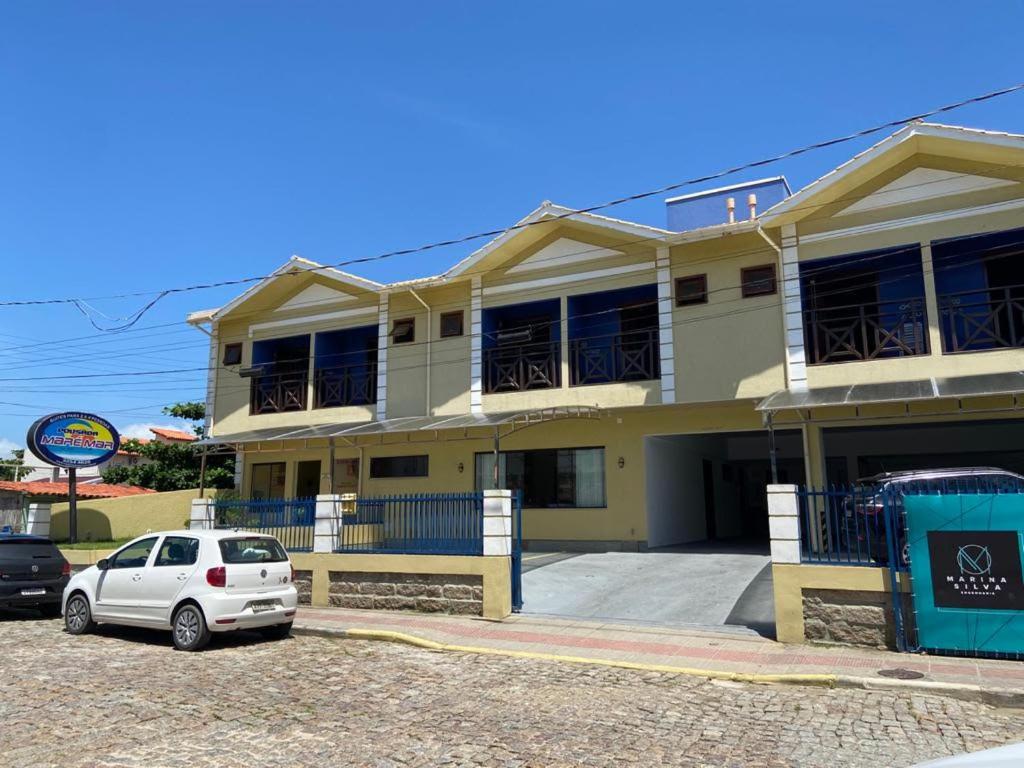 a white car parked in front of a building at Pousada Maré Mar in Garopaba