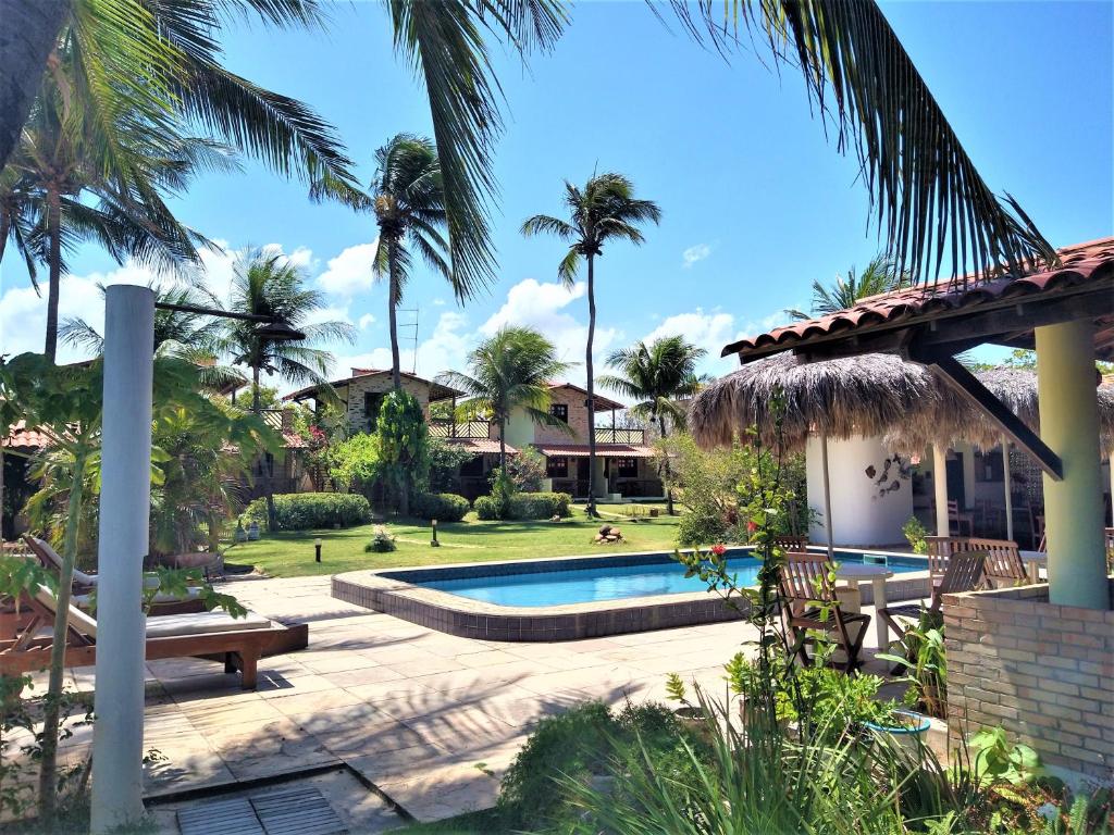 a villa with a swimming pool and palm trees at Arco Mundial Taíba in Taíba