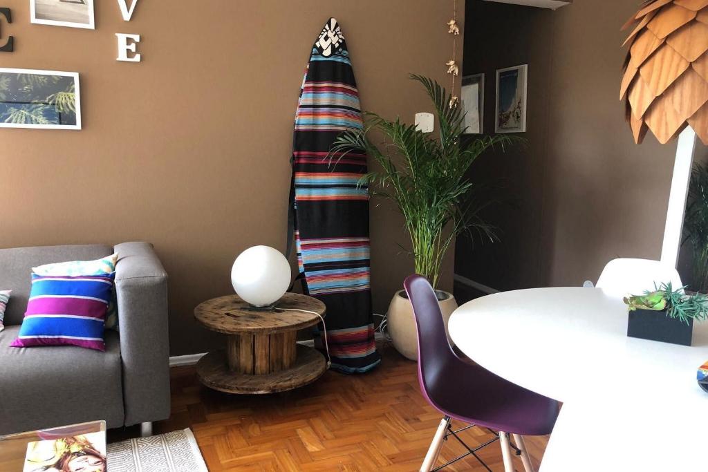 Hotel Iluminado Apartamento em Ipanema c/ wi fi, a pé p/ Praia, a living room with a couch and a surfboard at Iluminado Apartamento em Ipanema c/ wi fi, a pé p/ Praia in Rio de Janeiro