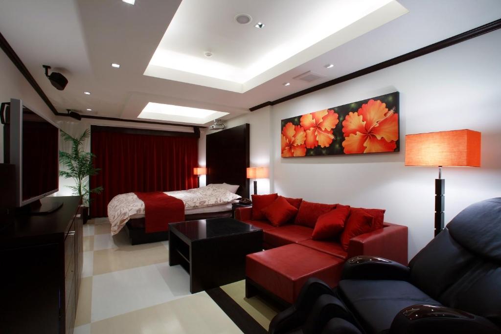 ein Wohnzimmer mit einem roten Sofa und einem Bett in der Unterkunft Hotel Water Gate Tokuyama adult only in Shunan