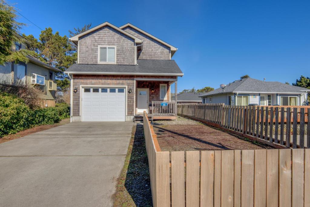 a house with a fence and a white garage at By The Sea-Seaside in Seaside