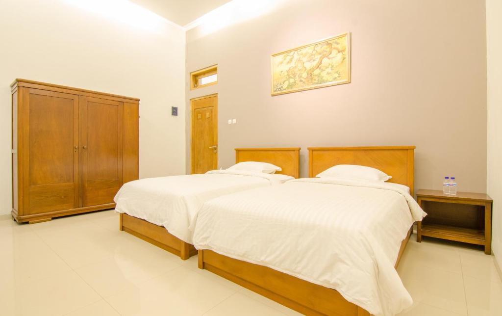 a bedroom with two beds with white sheets at Helena Guest House in Rampal