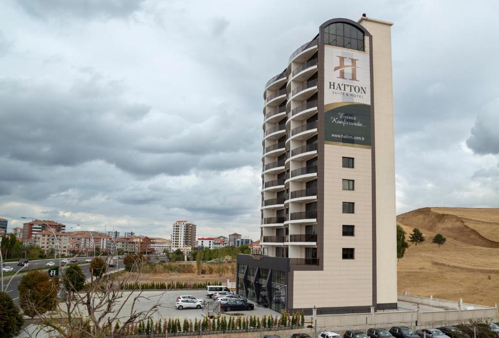 a building with a sign on it next to a parking lot at Hatton Suites Hotel Esenboga in Ankara