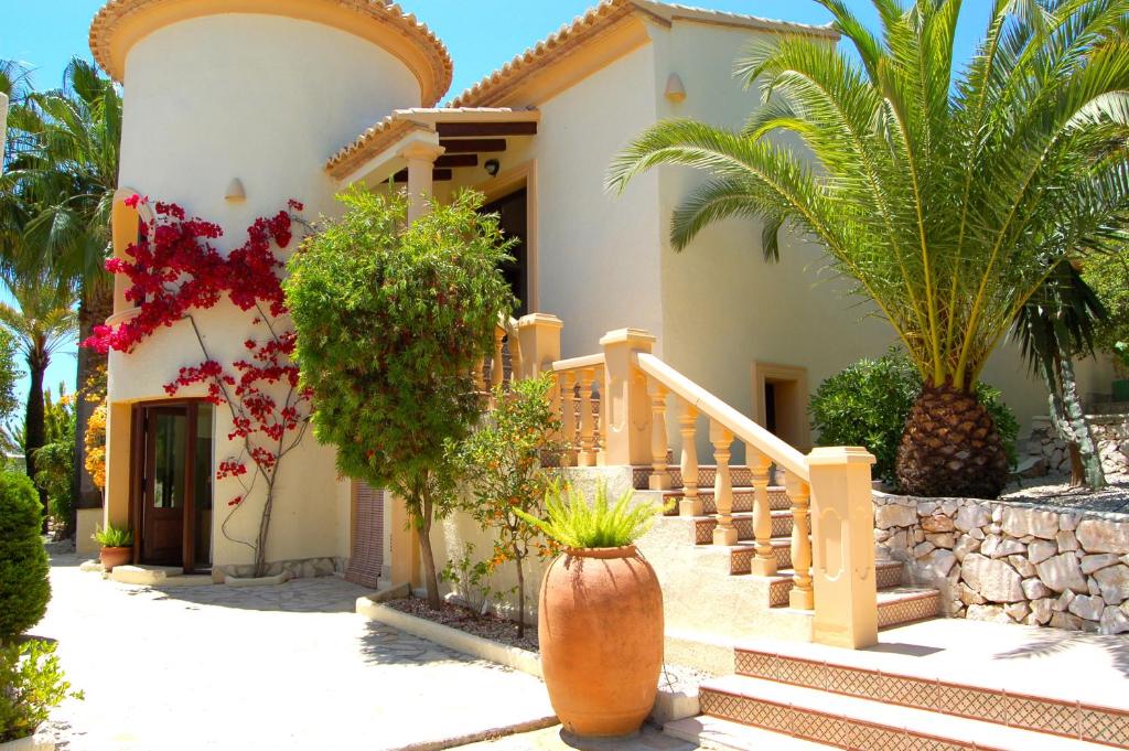 ein Haus mit einer Treppe und Palmen davor in der Unterkunft Fantastic villa with sea views pool and garden in Teulada
