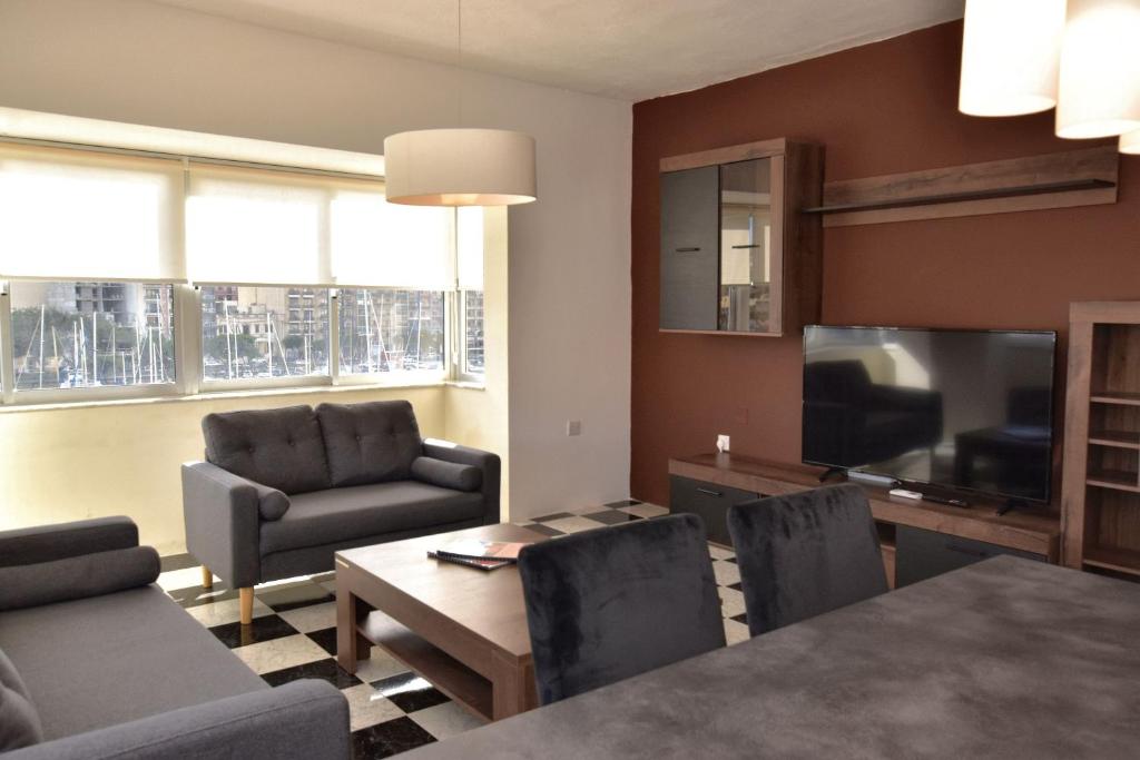 sala de estar con mesa, sillas y TV en 2 Bedroom, Bright & Central Top Floor Apartment - 5, en Msida