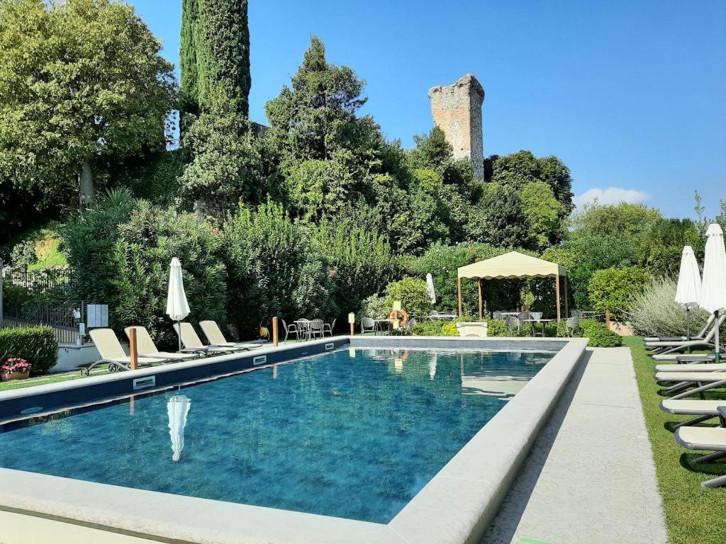 a swimming pool with lounge chairs and umbrellas at Residence Villa Antica Torre in San Felice del Benaco