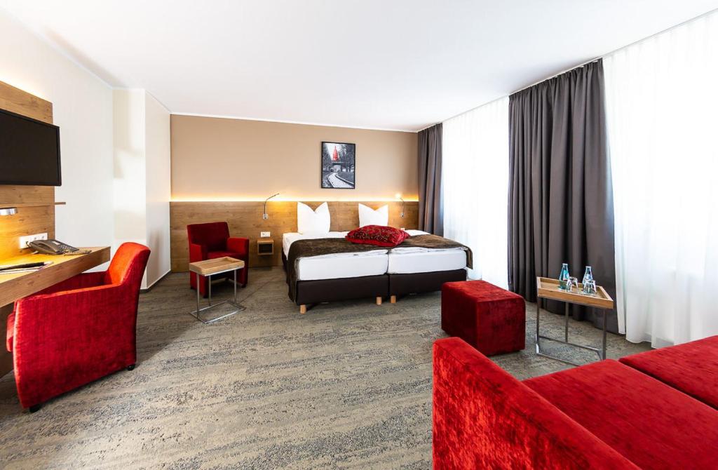 フランクフルト・アム・マインにあるマインガウ ホテルのベッドと赤い家具が備わるホテルルームです。