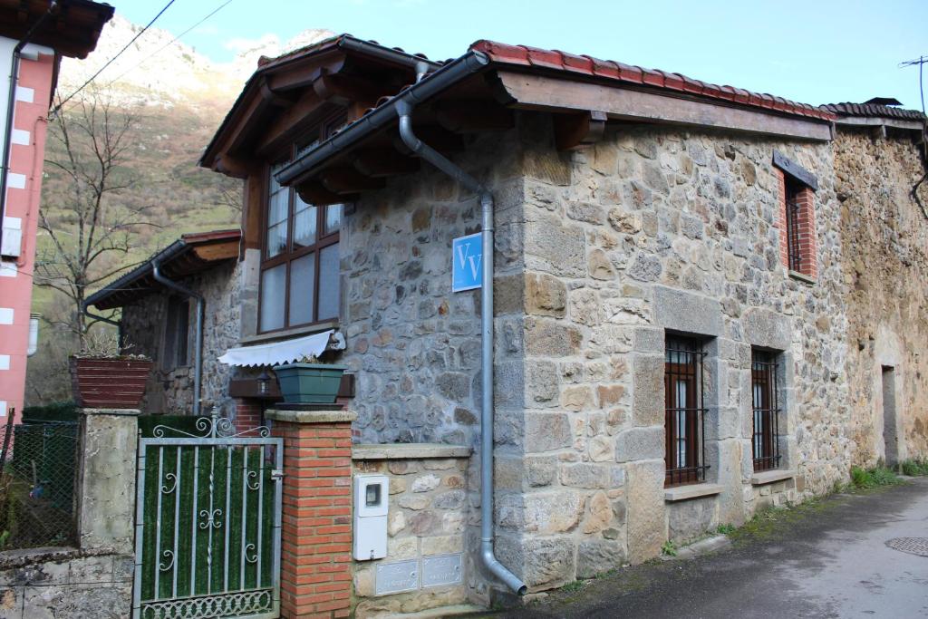 un viejo edificio de piedra con un letrero azul. en Vivienda Vacacional La Casina de Tina - Casas de los Picos, en Mier