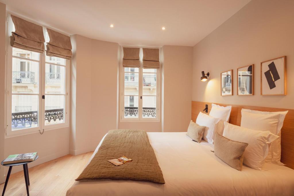 um quarto com uma cama grande e 2 janelas em Tinah Paris, Champs Elysées em Paris