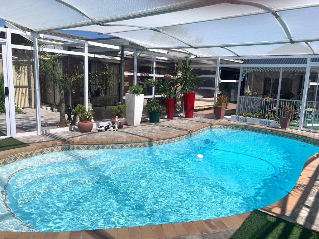 a large swimming pool with an umbrella over it at Arum Field Accommodation in Table View