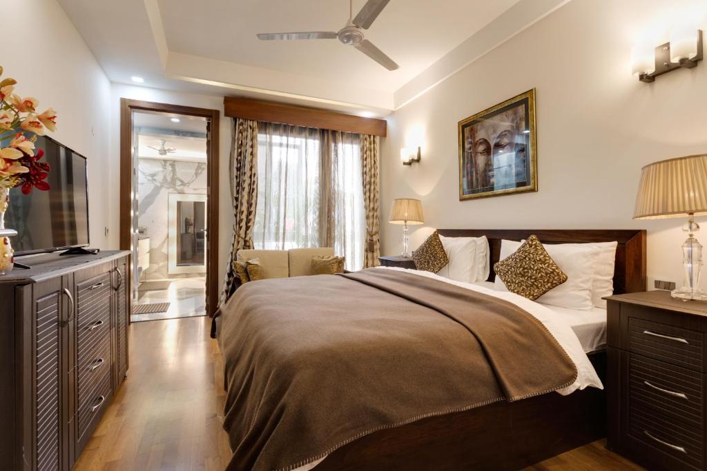 - une chambre avec un grand lit et une télévision dans l'établissement Ishatvam-4 BHK Private Serviced apartment with Terrace, Anand Niketan, South Delhi, à New Delhi