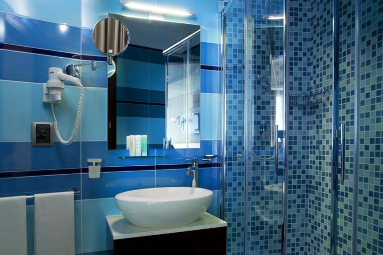 a blue bathroom with a sink and a shower at Taormina Panoramic Hotel in Taormina