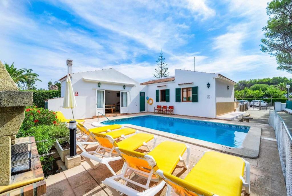 a villa with a swimming pool and yellow chairs at Casa Belleza in Cala en Blanes