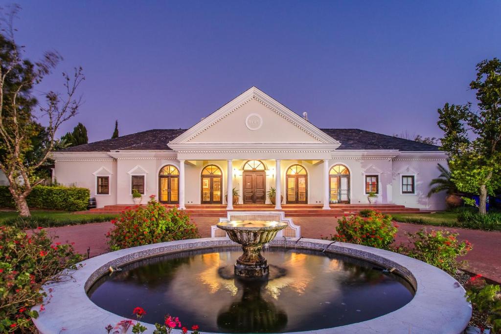 ein großes Haus mit einem Brunnen davor in der Unterkunft Bakenhof Winelands Lodge in Paarl