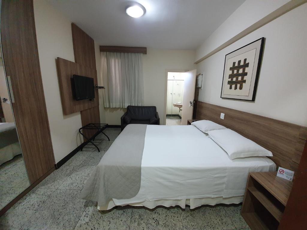 a hotel room with a bed, desk and a television at Via Contorno Hotel in Belo Horizonte