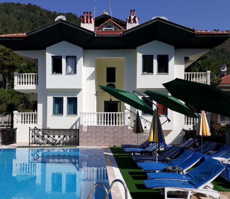 a pool with chairs and umbrellas in front of a house at Peaceful Villa with Shared Pool Surrounded by Calming Nature in Marmaris in Muğla