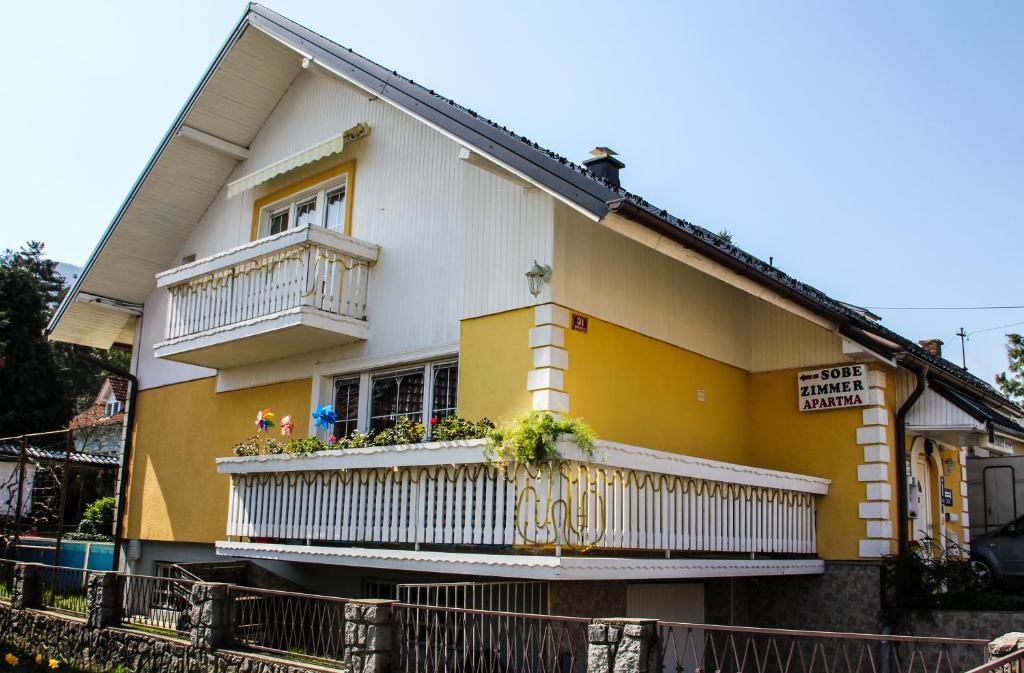 a yellow and white house with a balcony at Mekina Guesthouse in Maribor