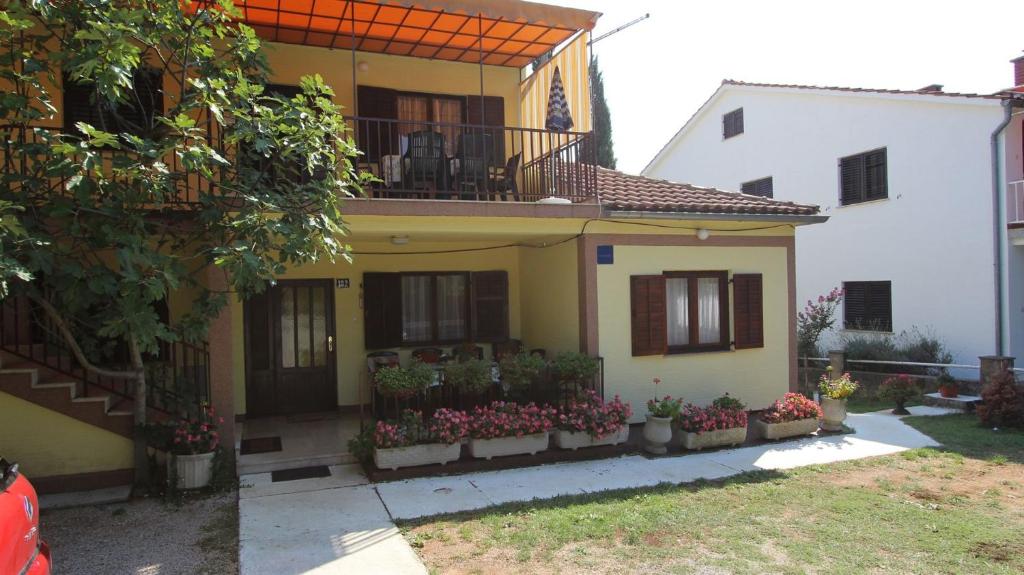 a yellow house with flowers in front of it at Apartments Trupec in Malinska