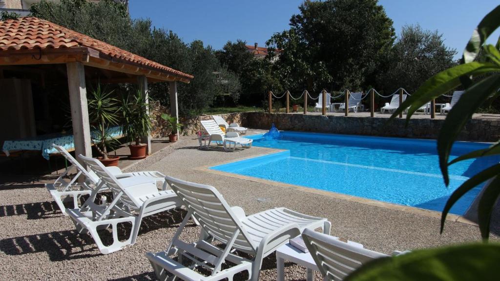 eine Gruppe von Stühlen neben einem Swimmingpool in der Unterkunft Apartments Kirinčić in Sveti Vid-Miholjice
