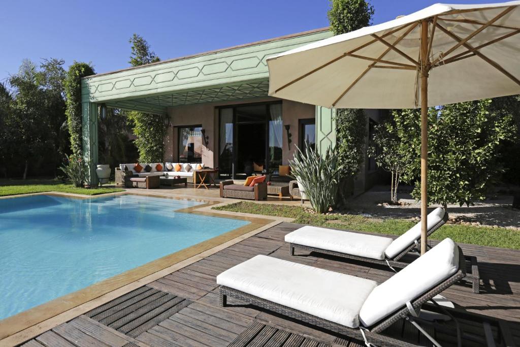 a pool with two lounge chairs and an umbrella at Villa MEZIANE avec piscine privée en première ligne du golf d'Amelkis in Marrakesh