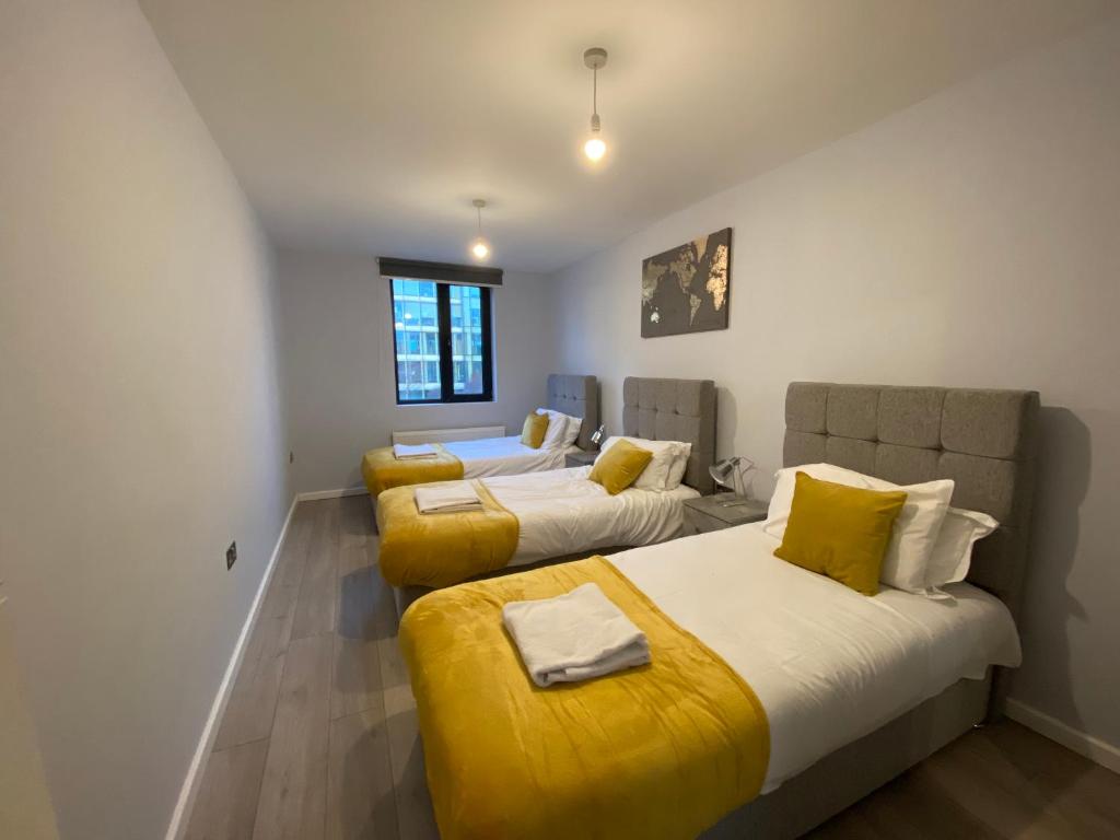 um quarto com 2 camas com almofadas amarelas em Zen Quality flats near Heathrow that are Cozy CIean Secure total of 8 flats group bookings available em Hounslow