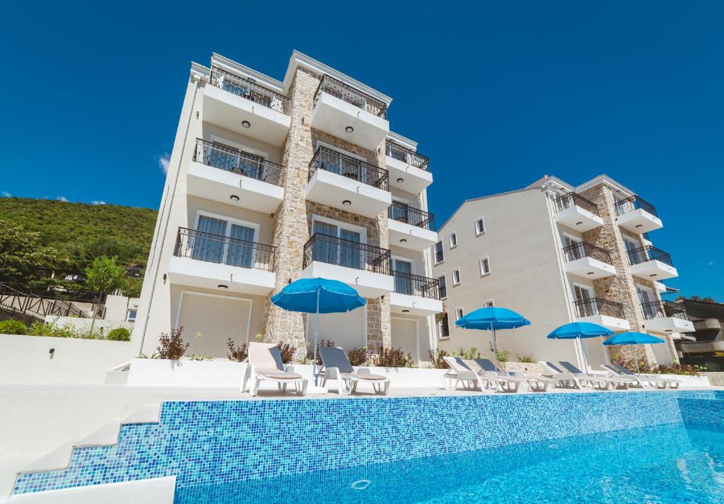 a hotel with a swimming pool and blue umbrellas at Villas Valentina in Bijela