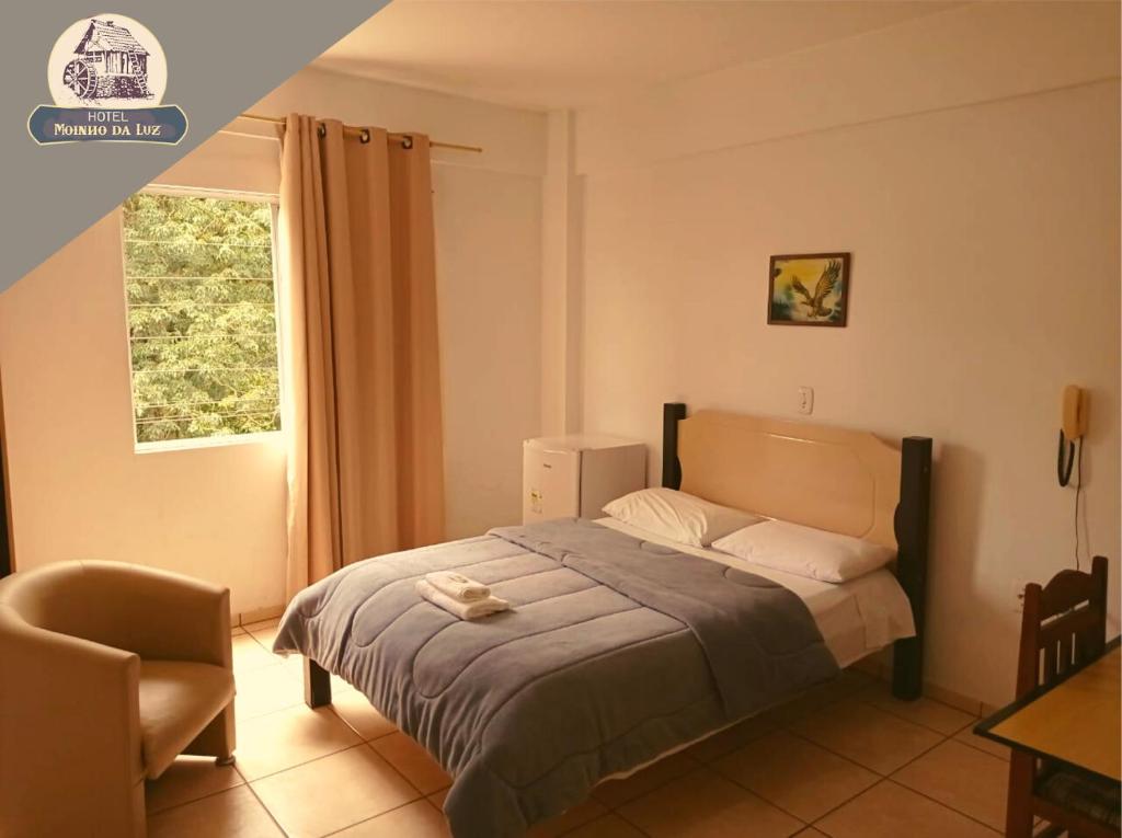 a bedroom with a bed with a chair and a window at Hotel Moinho da Luz - 10 minutos de Lajeado in Arroio do Meio