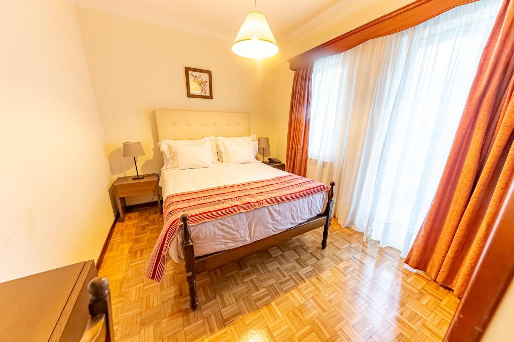 a bedroom with a bed and a large window at Beira Dão - Turismo Rural in Tondela
