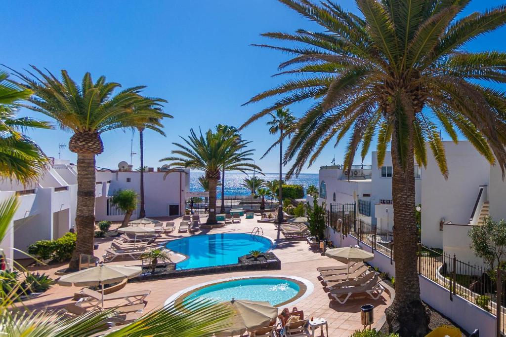 Blick auf ein Resort mit Pool und Palmen in der Unterkunft Apartamentos Flamingo in Puerto del Carmen